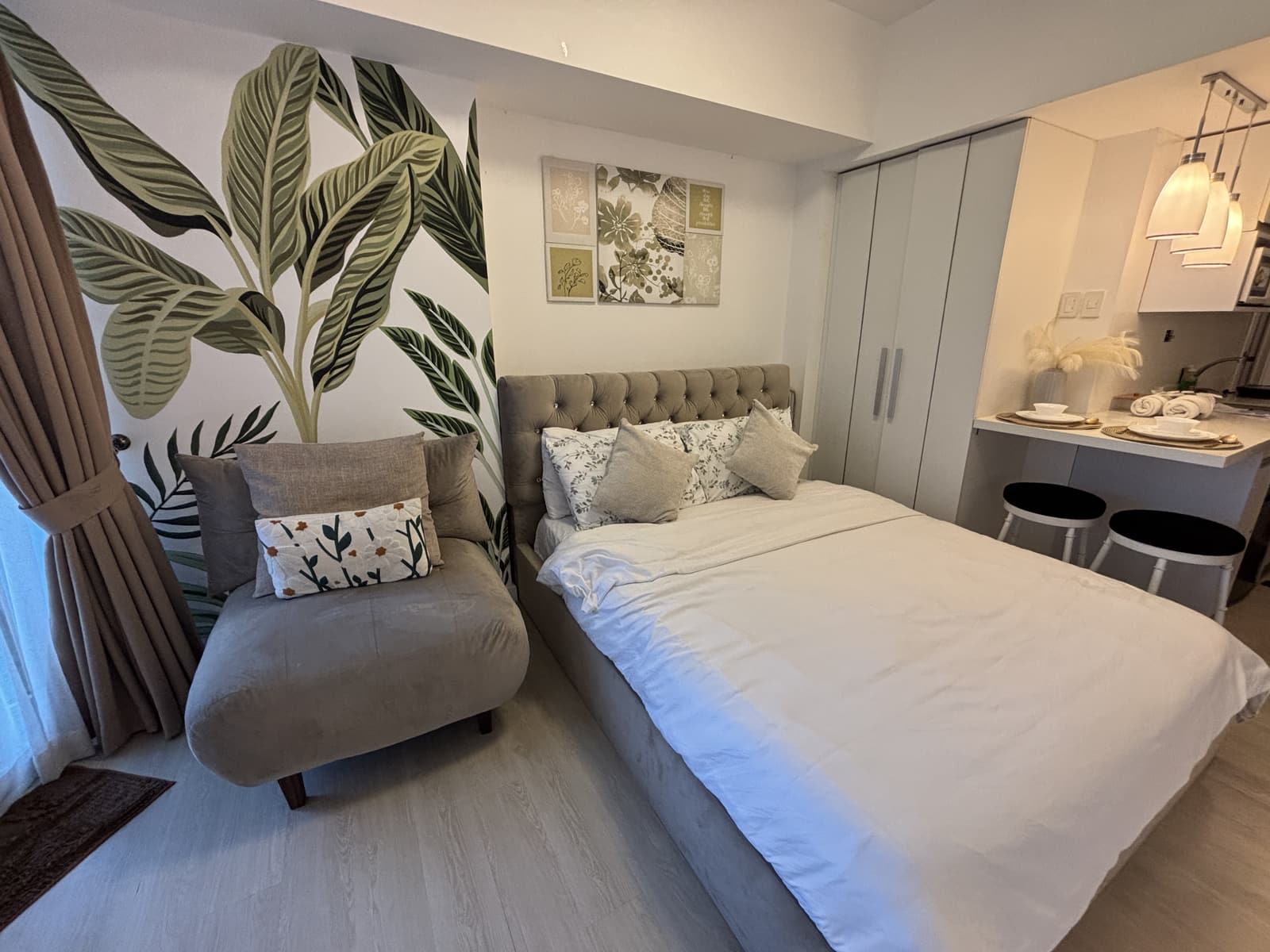 Queen bed with tropical leaf mural and cozy lounge chair