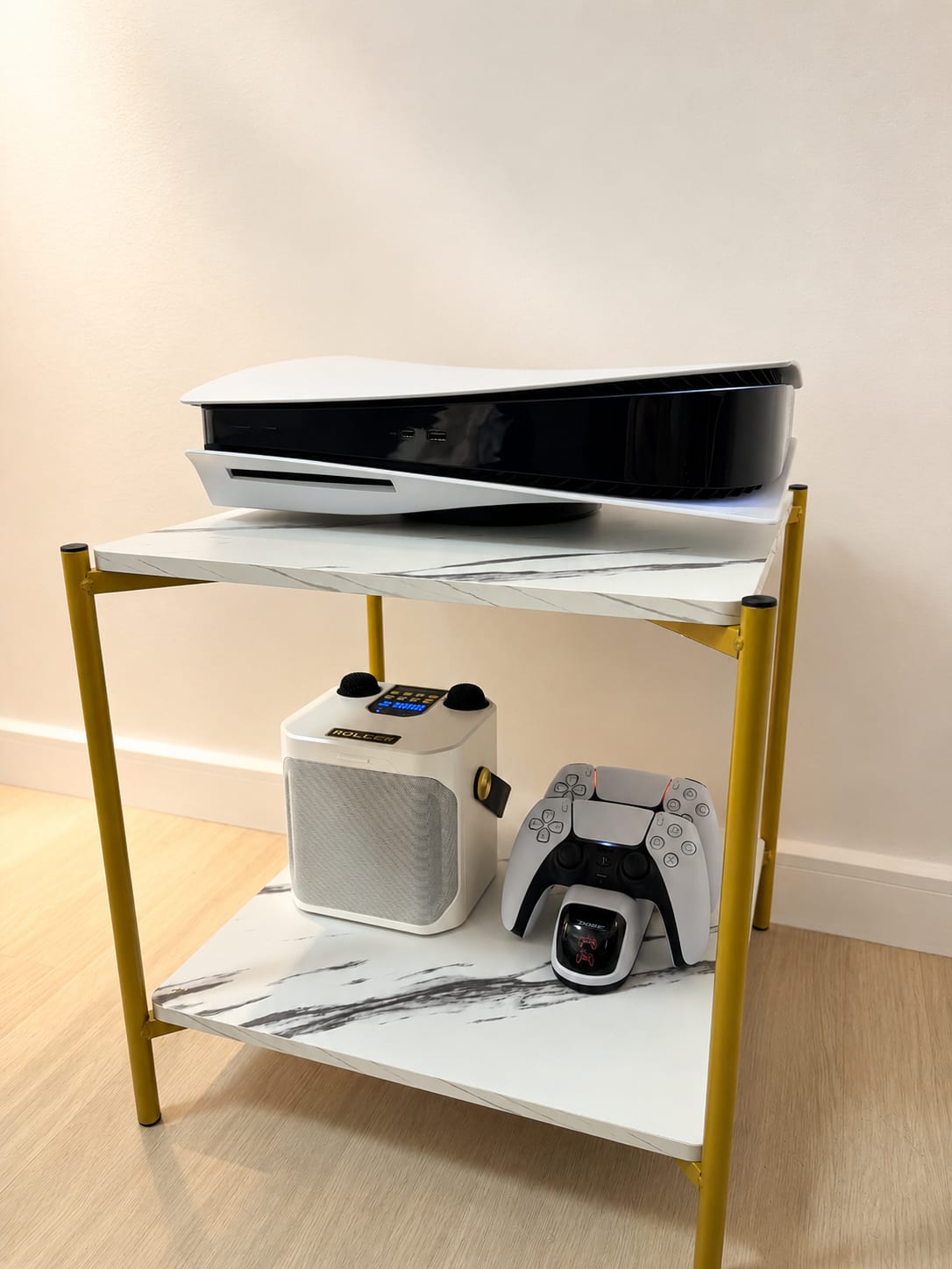 PlayStation 5 console on marble two-tier stand with karaoke speaker and DualSense controller